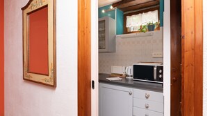 A kitchen with a microwave, cabinets, and a window with plants.