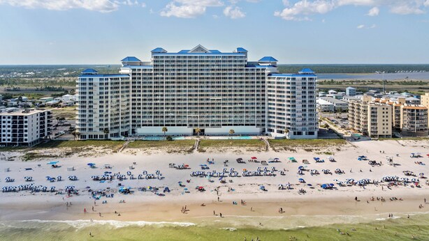 A large hotel with multiple floors and a beach in the foreground.