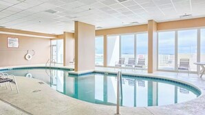 An indoor swimming pool with clear views of the city through large windows.