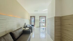 A modern hallway with a sofa, a small table, and a view of the outside through a door.