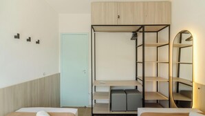 A compact room with a bunk bed, a wardrobe, a desk, and a mirror.