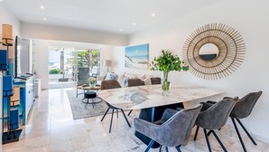 A modern dining area with a marble table, grey upholstered chairs, and a large mirror on the wall. - Casa Aurora - Vale do Lobo (Vale do Lobo)