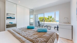 A modern bedroom with a large bed, a desk, and a balcony with a view of the sea. - Casa Aurora - Vale do Lobo (Vale do Lobo)