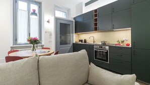 Una cocina moderna con armarios oscuros, horno empotrado y comedor con mesa y sillas.