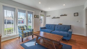A living room with a blue sofa, patterned armchair, and wooden coffee table. - Charming Craftsman in Downtown SJ (San Jose)