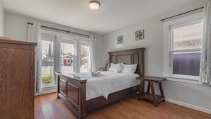 A bedroom with a wooden bed, a nightstand, and a view through a large window. - Charming Craftsman in Downtown SJ (San Jose)