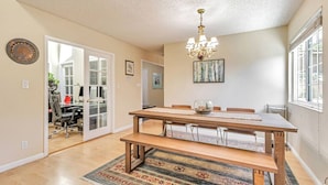 A dining area with a wooden table, benches, a chandelier, and a view of a room with a desk and chair. - Tranquil 3BDR/2BA Fremont Escape (Fremont)