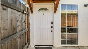 A white door with the number 3, a wooden fence, and a glass door with a view of a backyard.