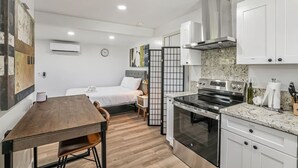 A compact hotel room with a kitchenette, a dining area, and a bed with a view.
