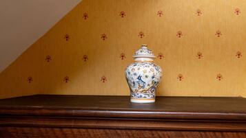 A ceramic vase on a wooden surface against a patterned wall.