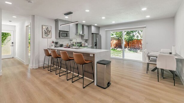 Una cocina moderna con una isla central, taburetes de bar y un comedor con mesa y sillas.
