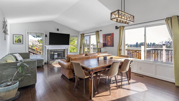 A spacious living room with a fireplace, a dining area, and large windows offering a view of the outdoors. - 4BR3.5BA w/Epic SJ Valley Views! (San Jose)