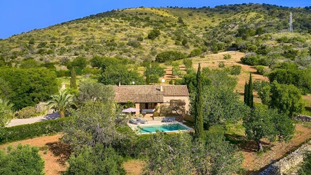 Une villa avec piscine, entourée d’une végétation luxuriante et de collines.