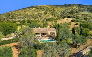 Une villa avec piscine, entourée d’une végétation luxuriante et de collines.