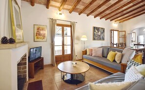 Un salon chaleureux avec une cheminée, un téléviseur, un canapé, une table basse et des œuvres d’art accrochées aux murs.