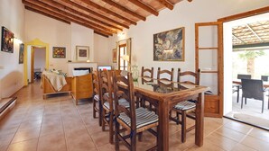 Un coin repas avec des chaises en bois et une table en verre, un lit avec une tête de lit jaune et un tableau accroché au mur.