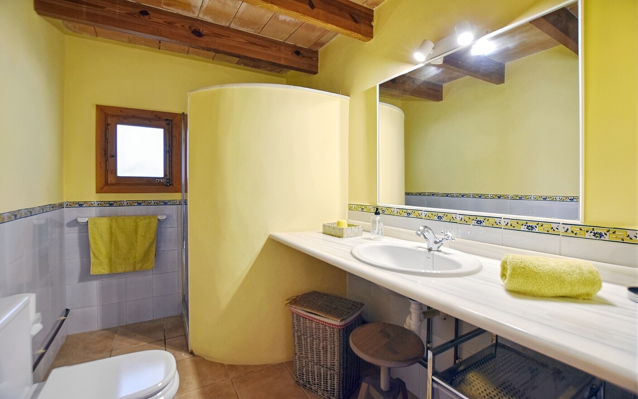 Ein Badezimmer mit Toilette, Waschbecken, Spiegel und Fenster.