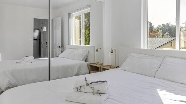 A modern hotel room with two beds, a large mirror, and a view of the outdoors. - Downtown 1bd/1ba ADU (Sunnyvale)