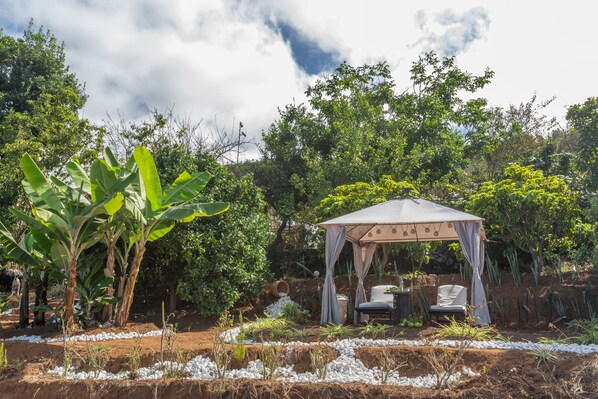 Jardí amb una glorieta, una cadira i una taula.