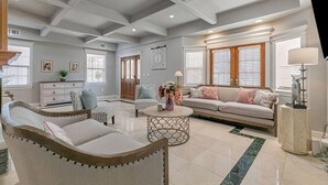 Un salon spacieux avec un grand canapé, deux fauteuils, une table basse et une chemin ée.