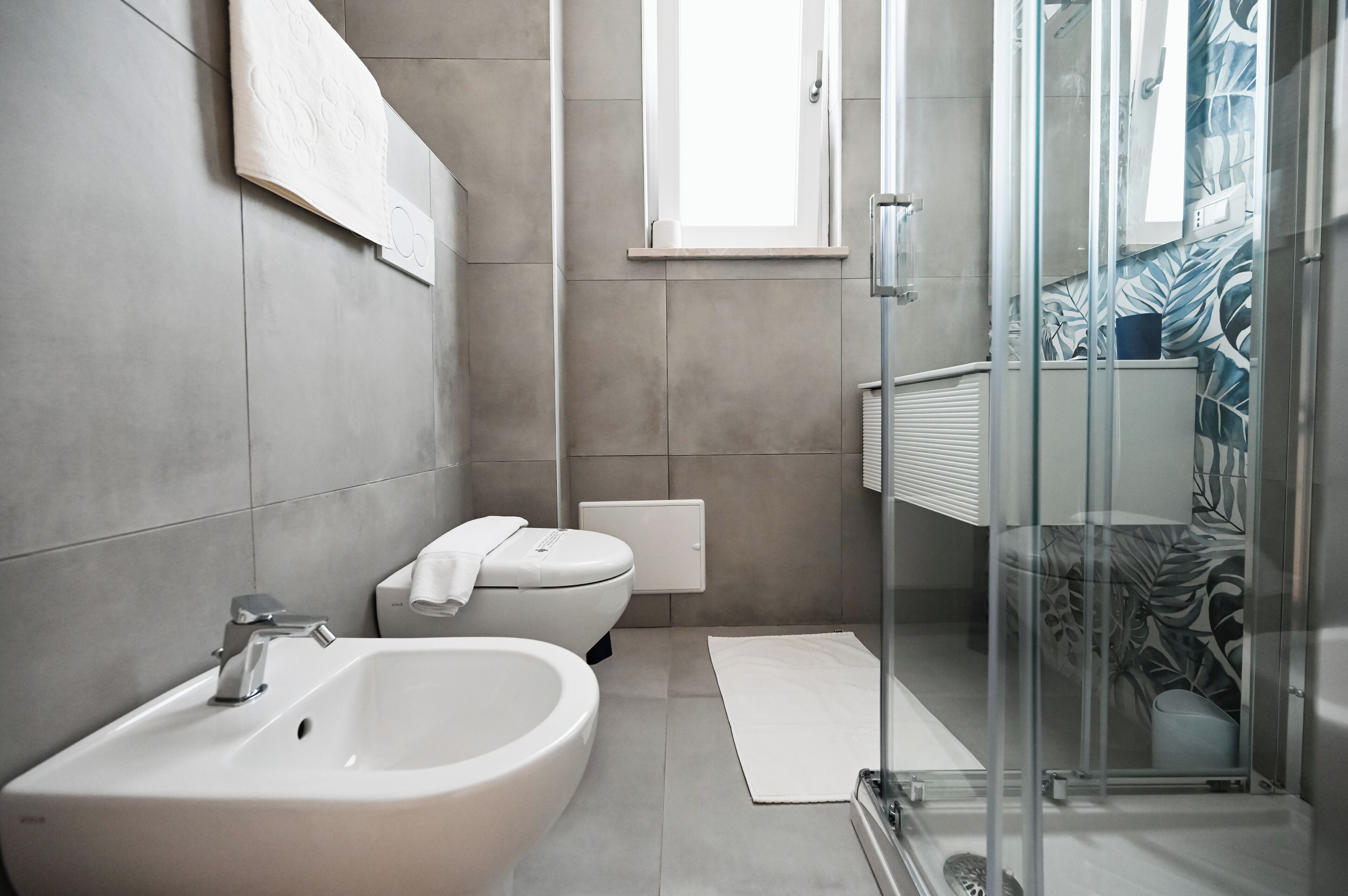 Un baño moderno con lavamanos, inodoro y ducha.