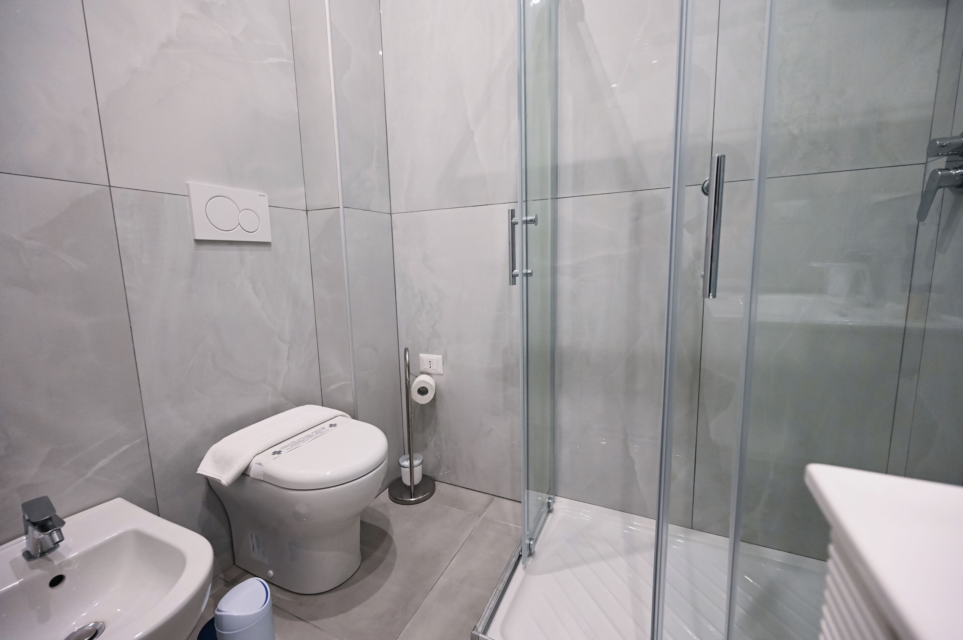 A modern bathroom with a toilet, sink, and glass shower enclosure.