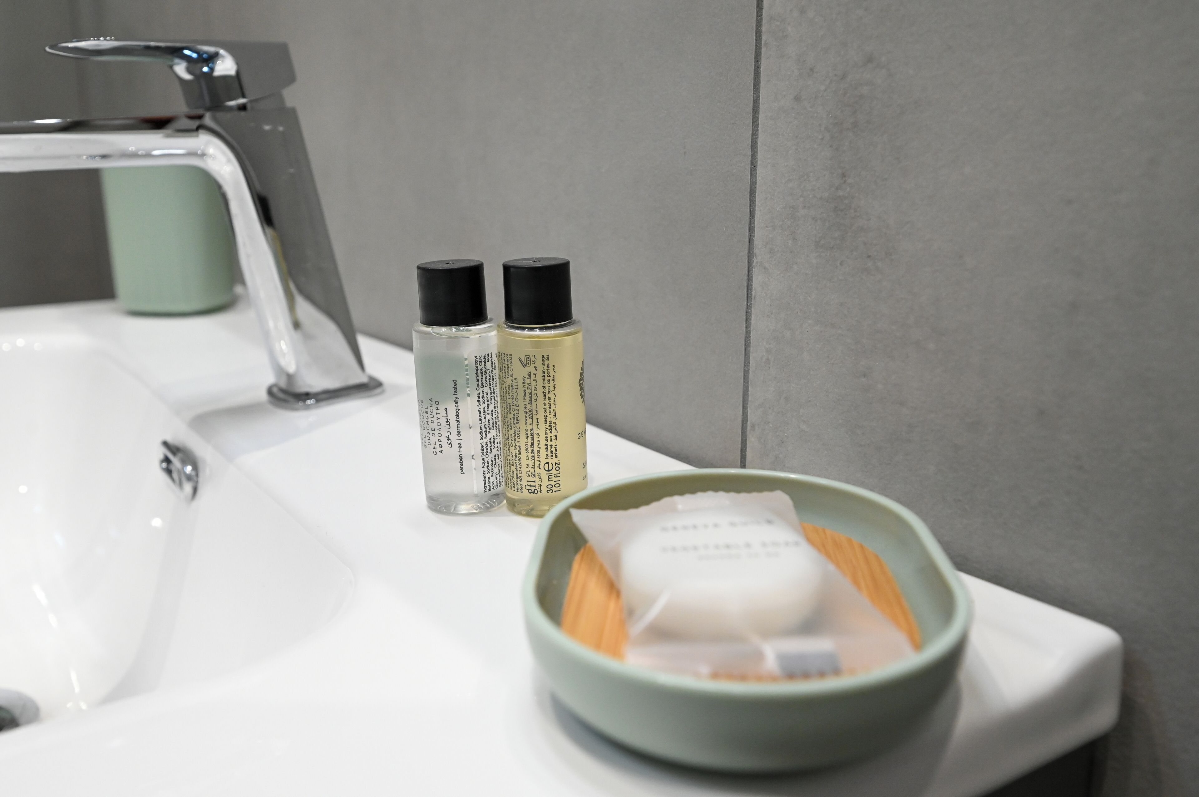 Un lavandino del bagno con due flaconi di sapone liquido e una saponetta sul ripiano.
