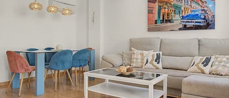 Un salon moderne comprenant un coin repas, un canapé et un tableau représentant une scène de rue.
