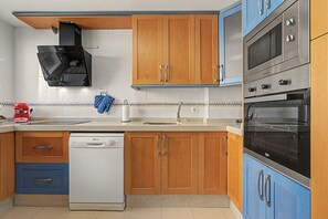 A kitchen with wooden cabinets, a dishwasher, a stove, and a microwave.