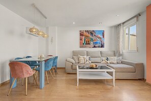 Una sala de estar moderna con comedor, un conjunto de sofá, una mesa de centro y un cuadro de una escena callejera.