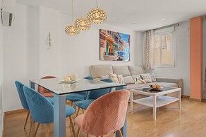 Un saló modern amb zona de menjador, que inclou un sofà, cadires, una taula de centre i un quadre a la paret.