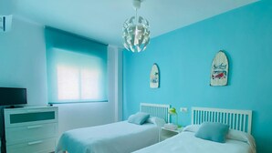 Une chambre avec deux lits, une télévision et une fenêtre.