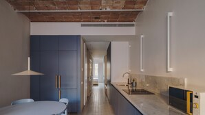 Una cocina moderna con horno integrado, un lavabo y una zona de comedor con mesa y sillas.