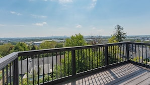 Une terrasse en bois avec une rambarde donnant sur un paysage urbain.