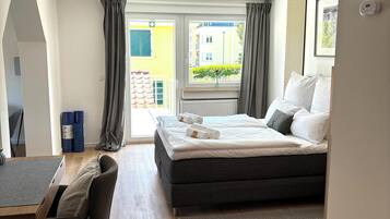A modern hotel room with a bed, a desk, and a view of the outside.