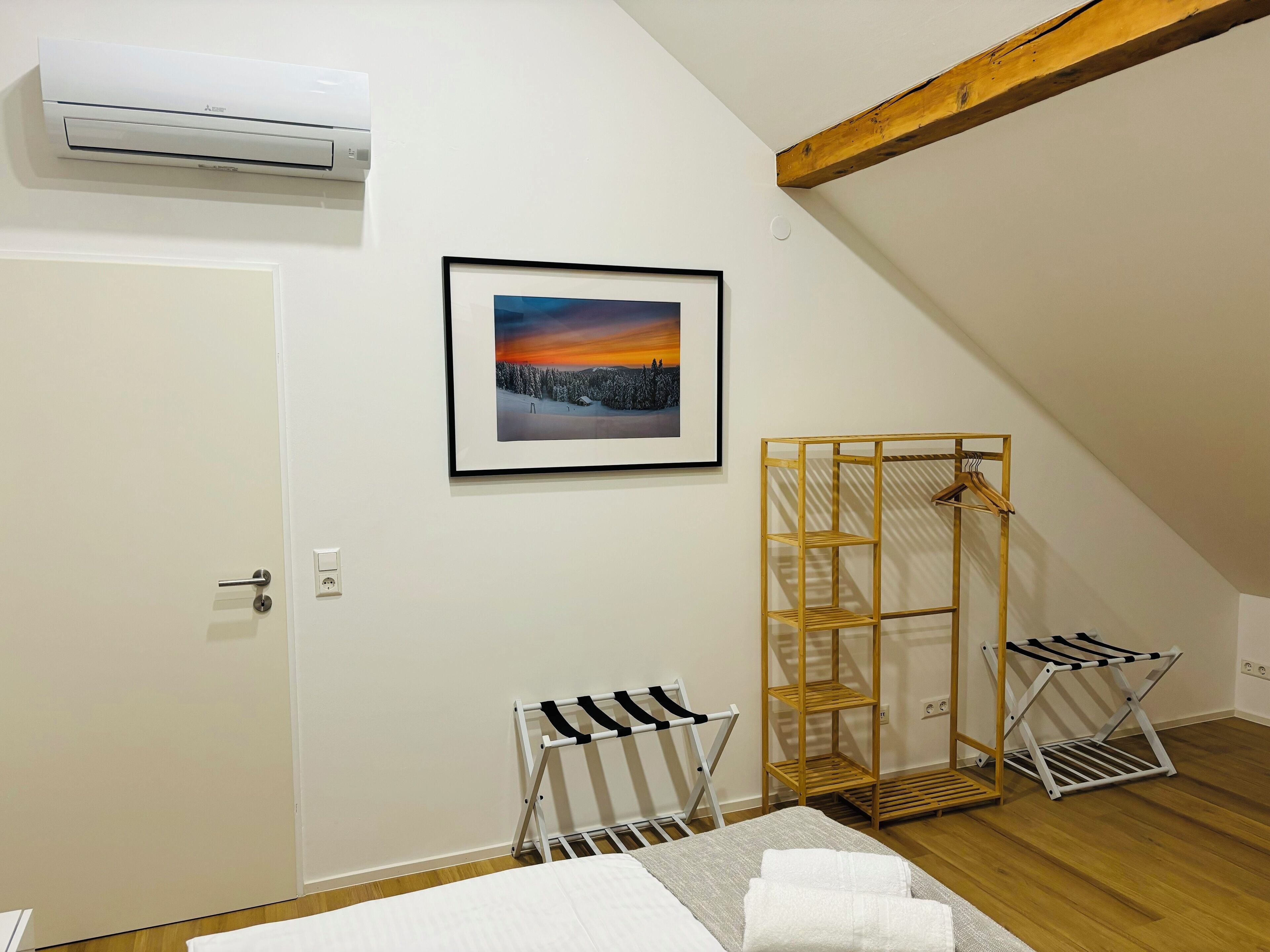 Une chambre à coucher avec un lit, un tableau encadré, un climatiseur et une poutre en bois.