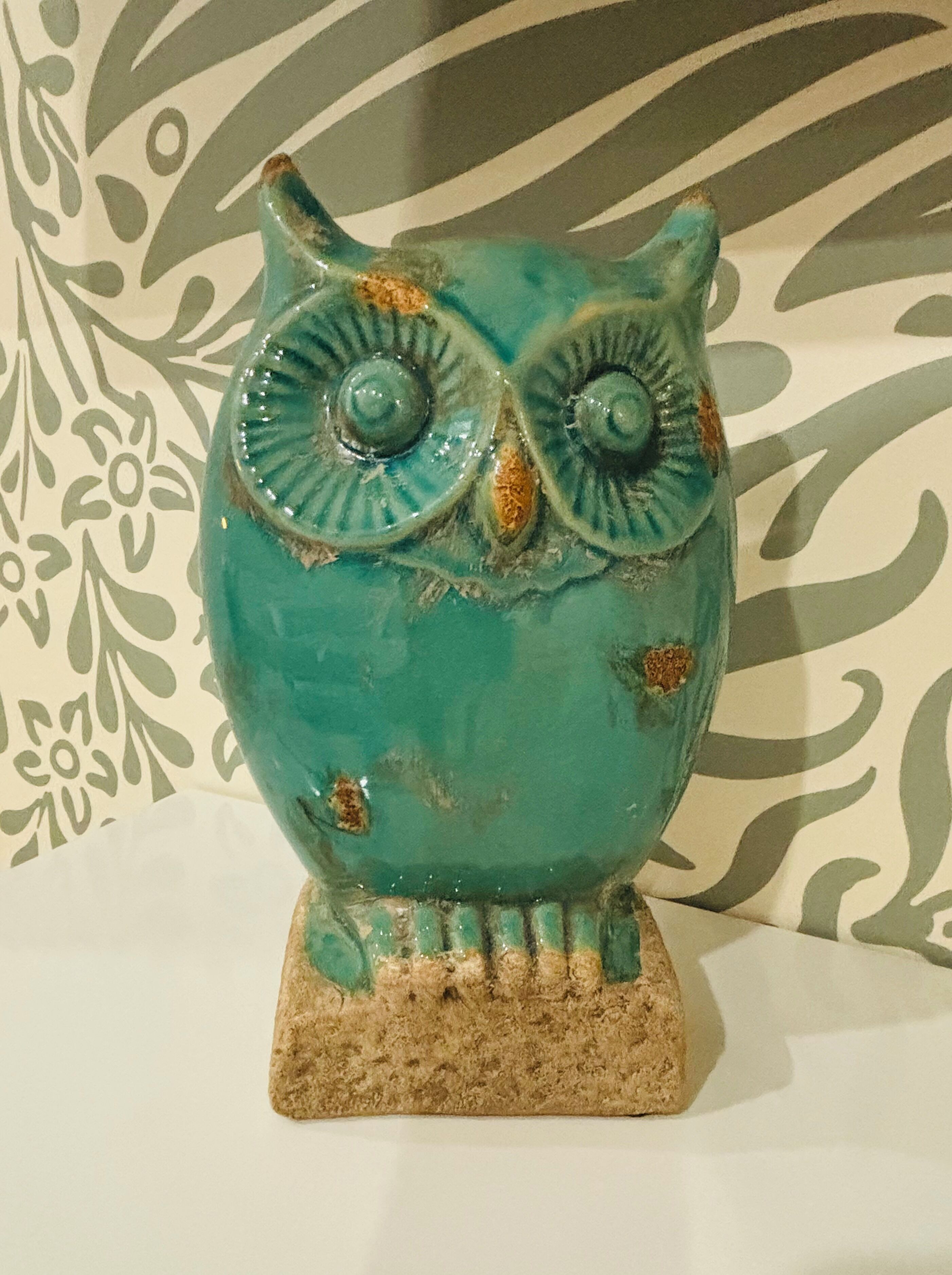 Een turquoise keramieken uilbeeldje met een gestructureerde basis, voor een achtergrond met patroon.