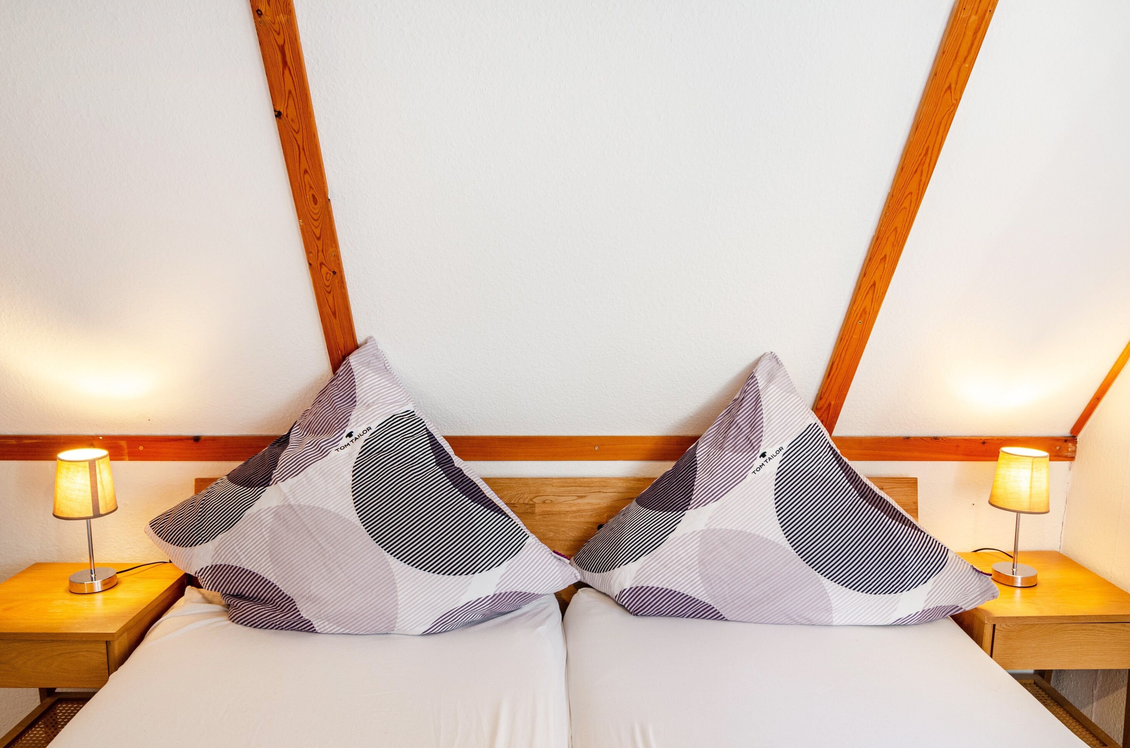 Un lit avec deux oreillers, deux lampes de chevet et une tête de lit en bois.