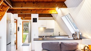 A modern kitchen with white cabinets, a black clock, and a window above the sink. - Holiday Home 'Twistesee 42' (Bad Arolsen)