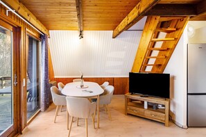 Un intérieur en bois comprenant une table à manger, des chaises, un téléviseur et un réfrigérateur.