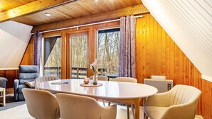 A cozy room with a wooden ceiling, a large oval table with chairs, a sofa, and a radiator. - Holiday Home 'Twistesee 42' (Bad Arolsen)