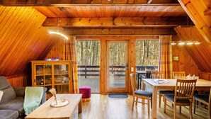 A cozy cabin interior with a dining area, a sofa, a cabinet with glass doors, and a view through the door. - Holiday Home 'Twistesee 36' (Bad Arolsen)