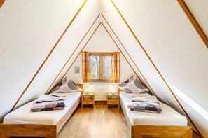 Un dormitorio abuhardinado triangular con dos camas, una ventana y un radiador.