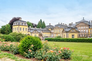 A large, multi-story building with a symmetrical facade, surrounded by well-maintained gardens and a clear sky. - Holiday Home 'Twistesee 36' (Bad Arolsen)