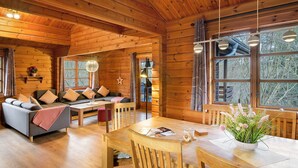 A wooden cabin interior with a sofa, dining table, and chairs.