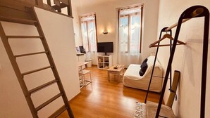 A compact living space with a loft bedroom, a sofa, a TV, and a small dining area. - Chez Giulia Cassis - Studio near the beach (Cassis)