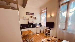 A compact living space with a kitchenette, a dining area, and a TV. - Chez Giulia Cassis - Studio near the beach (Cassis)