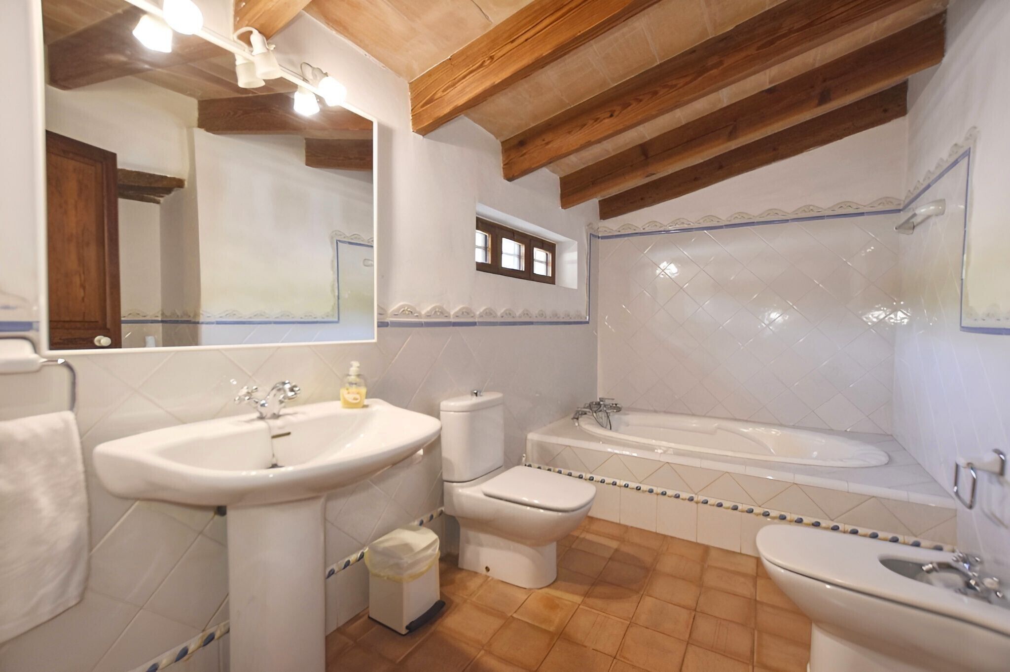 Een badkamer met een wastafel, toilet, bad en een spiegel.