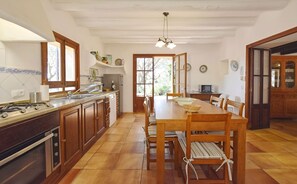 Una cocina con armarios de madera, una mesa de comedor y un horno empotrado.