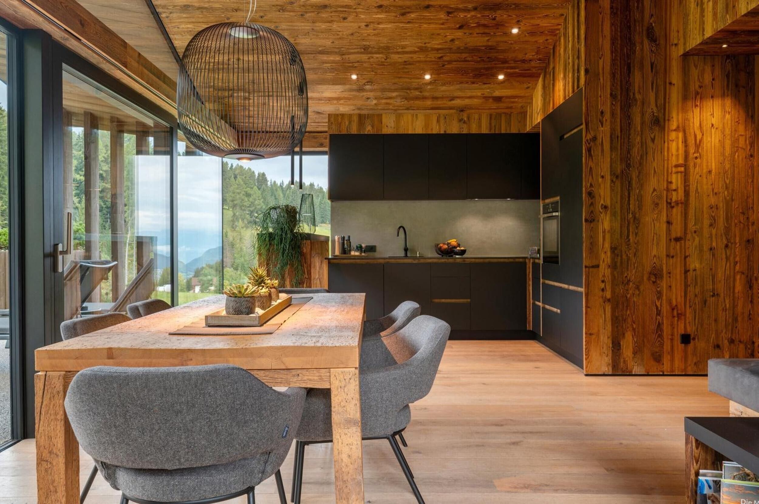 Una cucina moderna con una grande isola, soffitto in legno e vista sull'esterno.